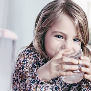 Fille qui boit de l'eau dans un verre